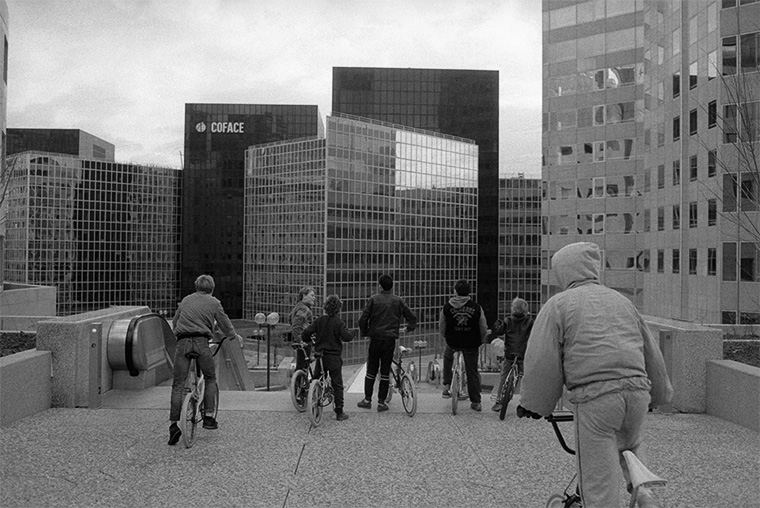 Des jeunes en vélo, admirent les bureaux de Paris la Défense, janvier 1987
